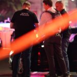 4, incluindo policial, atirando em uma arma no meio